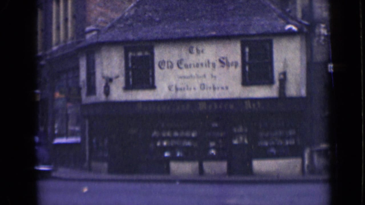 1946 London exterior of The Old Curiosity Shop, showing the signed facade and quiet street after traffic passes.