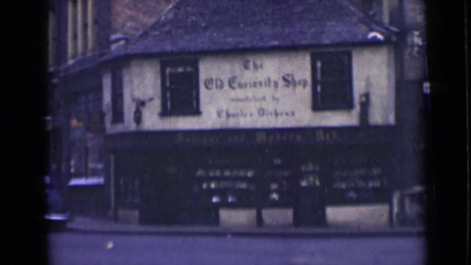 1946 London exterior of The Old Curiosity Shop, showing the signed facade and quiet street after traffic passes.