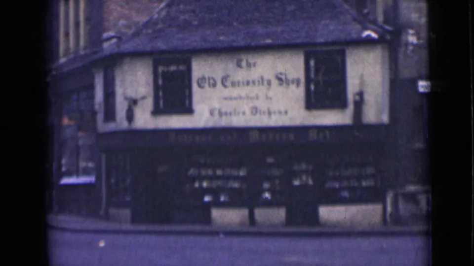 London 1946 home-movie frame of The Old Curiosity Shop facade, with upper windows and shopfront below.