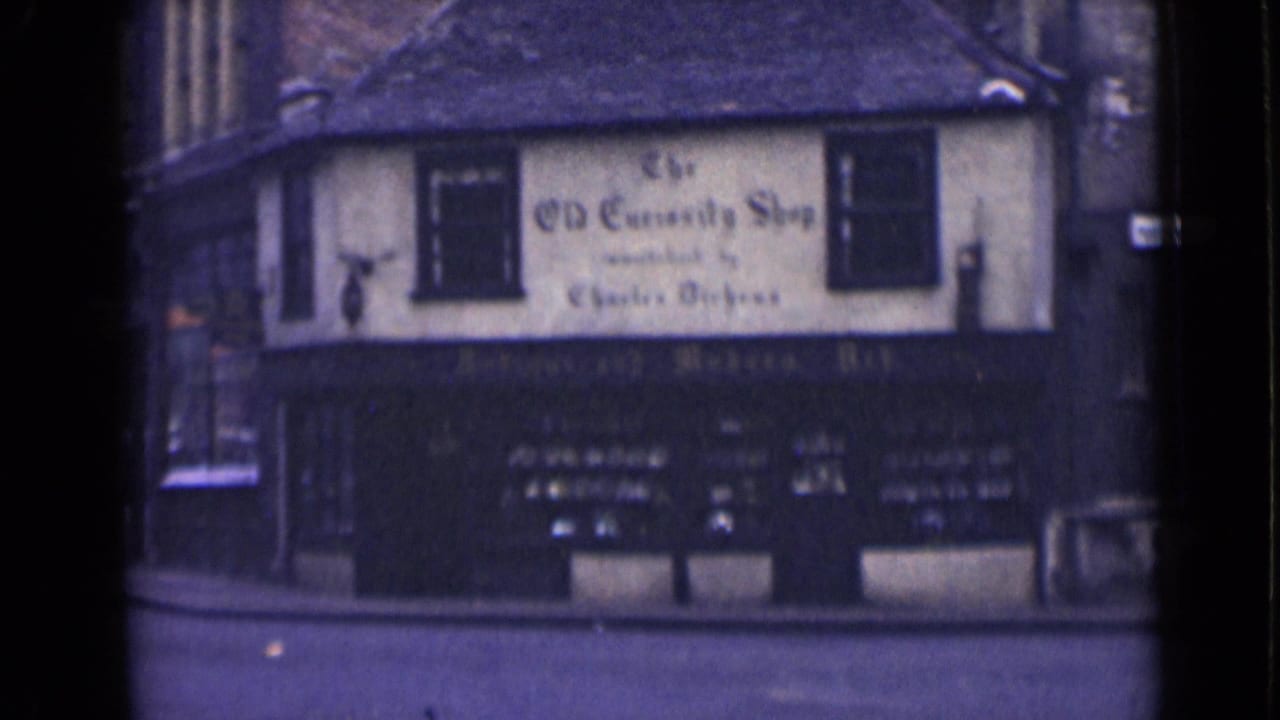 1946 London 8mm frame showing a corner building marked The Old Curiosity Shop, with upper windows and a dark storefront below.