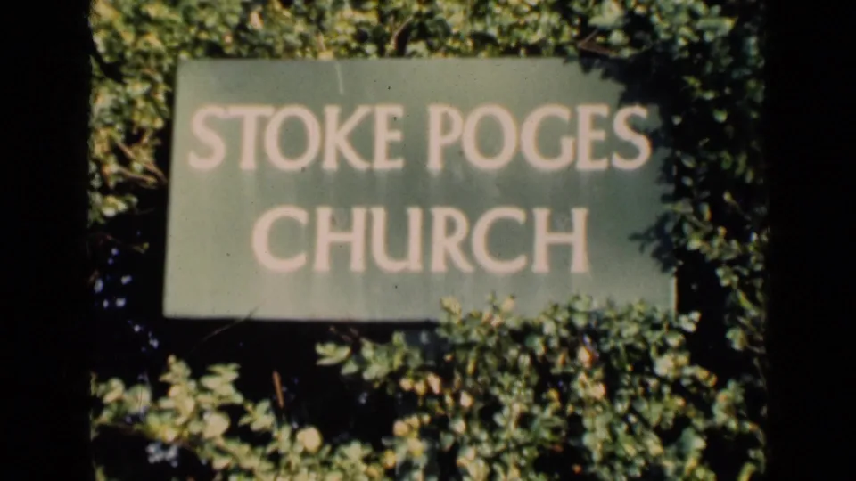 1946 England 8mm frame with a readable Stoke Poges Church sign set against leafy shrubs and garden growth.