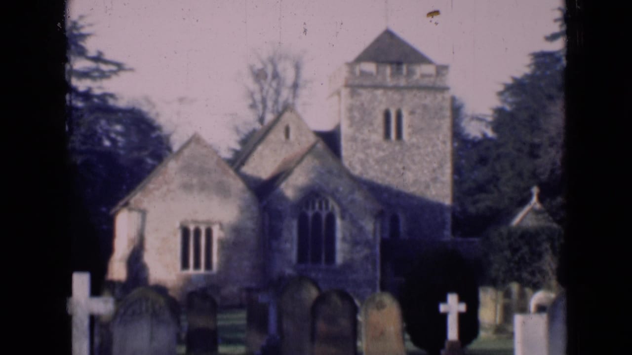 1946 London 8mm frame showing a stone church tower, arched windows, trees, and grave markers in a churchyard.