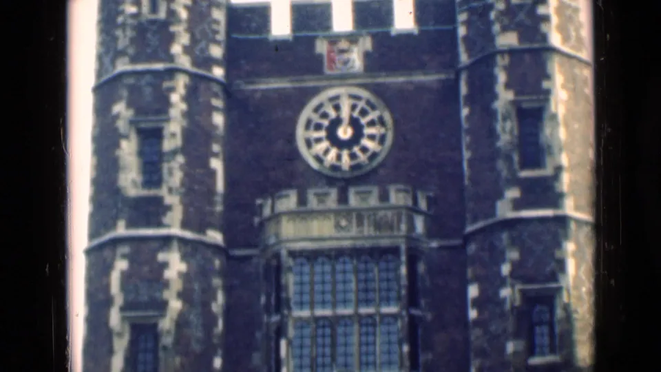 1946 London frame with the building clock centered above tall windows, flanked by rounded tower sections and pale stone accents.