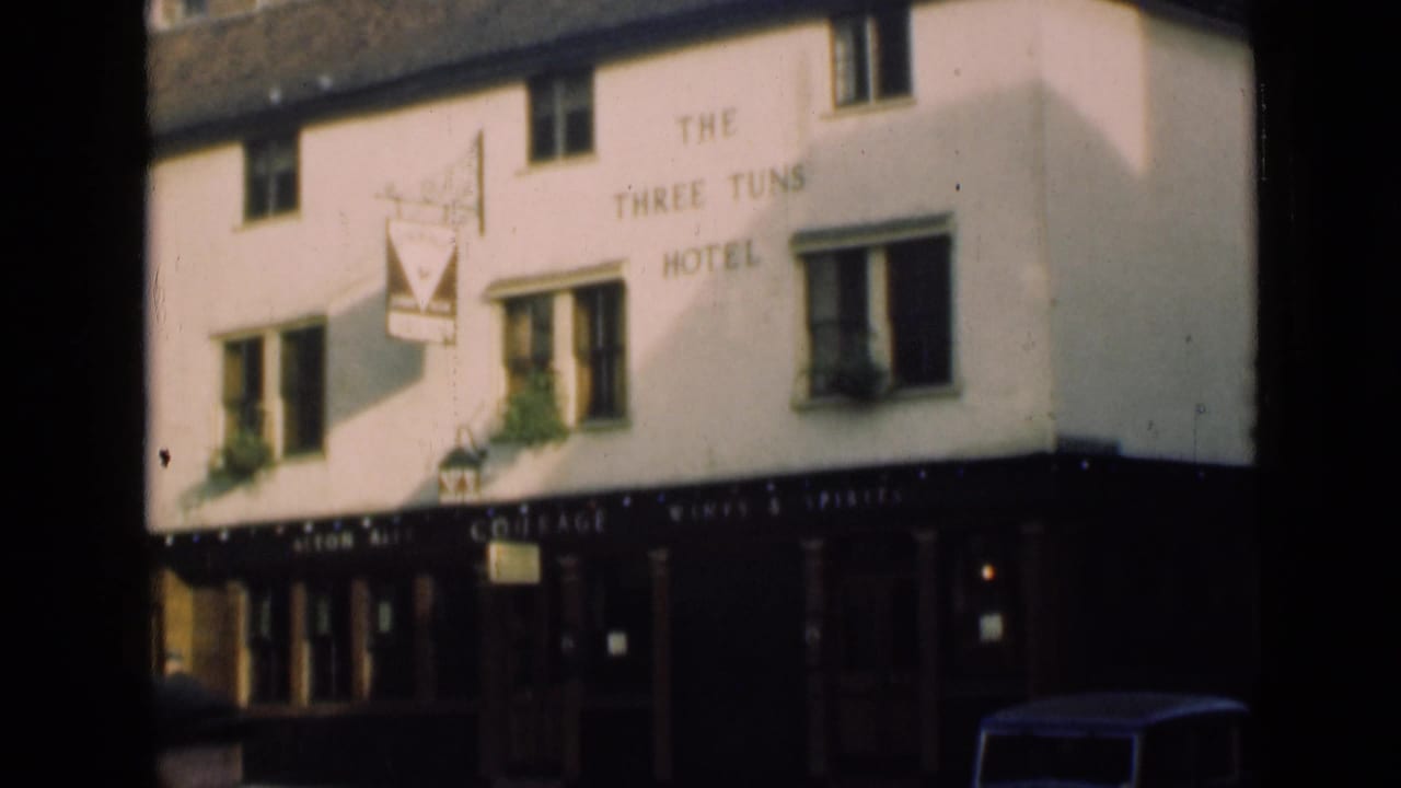 London hotel and pub exterior in 1946, showing The Three Tuns Hotel lettering, hanging sign, dark storefront, and parked car detail.