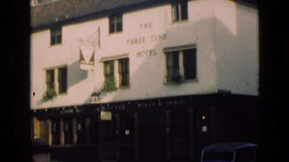 London hotel and pub exterior in 1946, showing The Three Tuns Hotel lettering, hanging sign, dark storefront, and parked car detail.