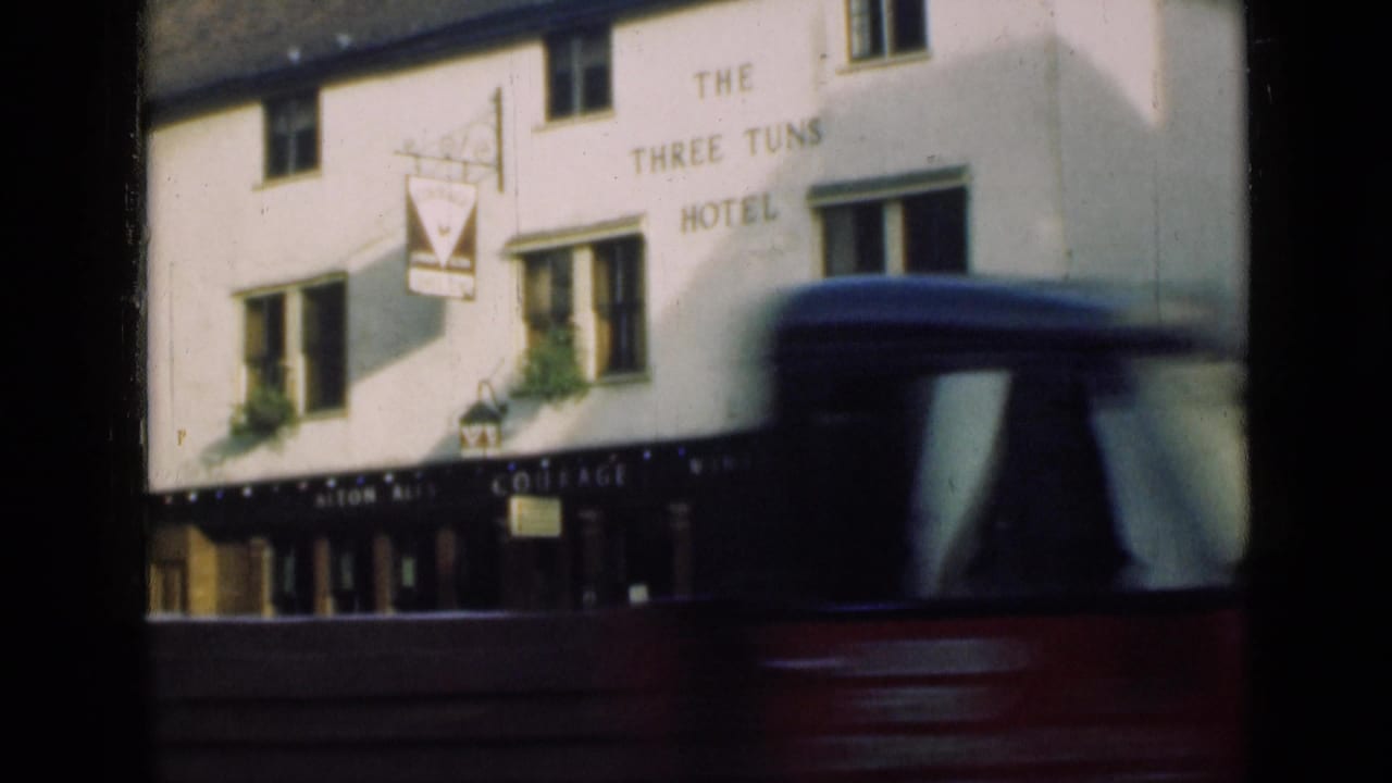 The Three Tuns Hotel in London is seen as a large passing vehicle crosses the foreground and obscures part of the frontage.