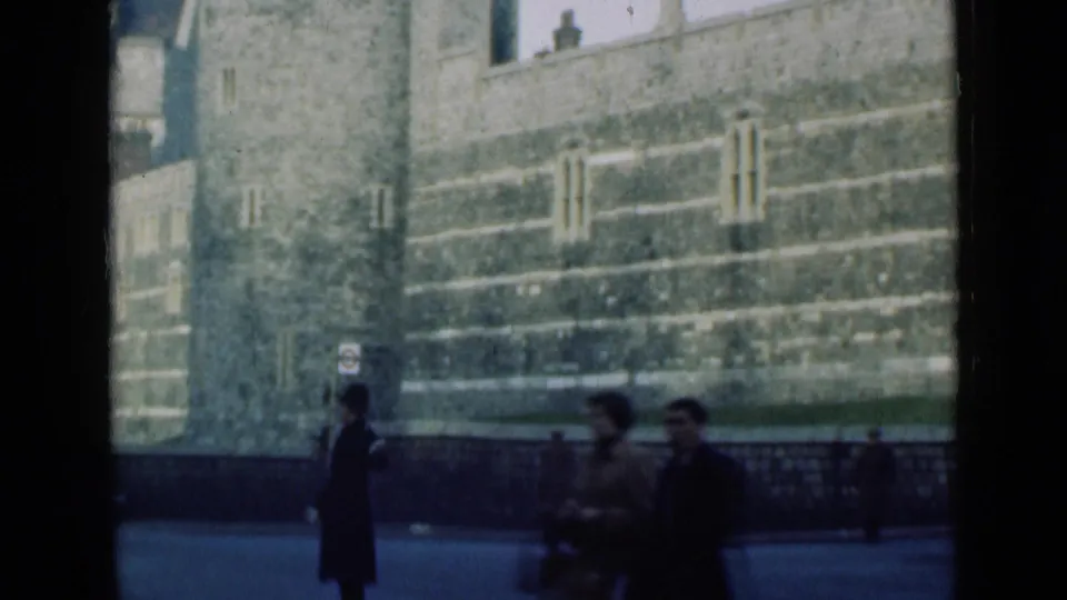 1946 London street view with pedestrians, a uniformed policeman, railings, and massive stone landmark walls in the background.