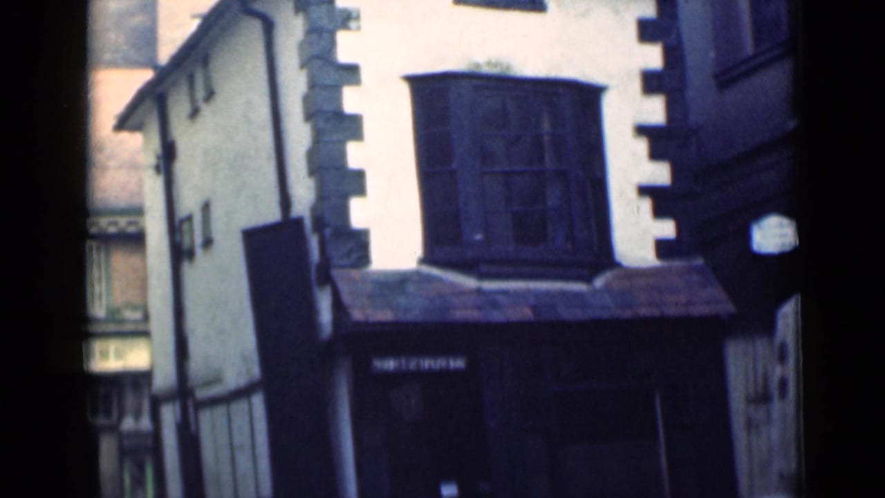 White stucco building with dark stone quoins and a projecting bay window.