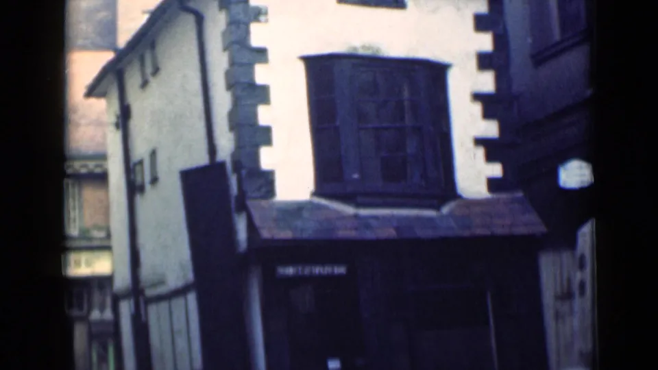 1946 London home-movie frame showing a white stucco facade, dark quoins, and a projecting upper bay window.