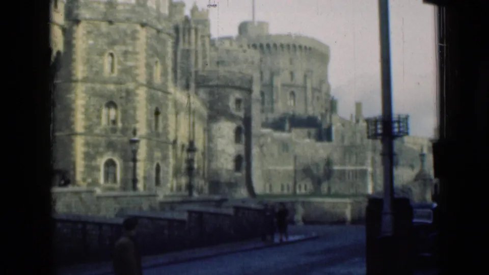 1940s 8mm footage shows the castle walls and towers with pedestrians below and a pole crossing the right side of the frame.