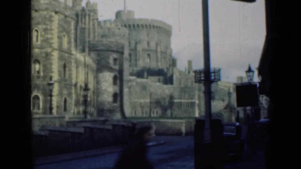 1946 8mm view of Windsor Castle stone towers and battlements from a street-level position under an overcast sky.