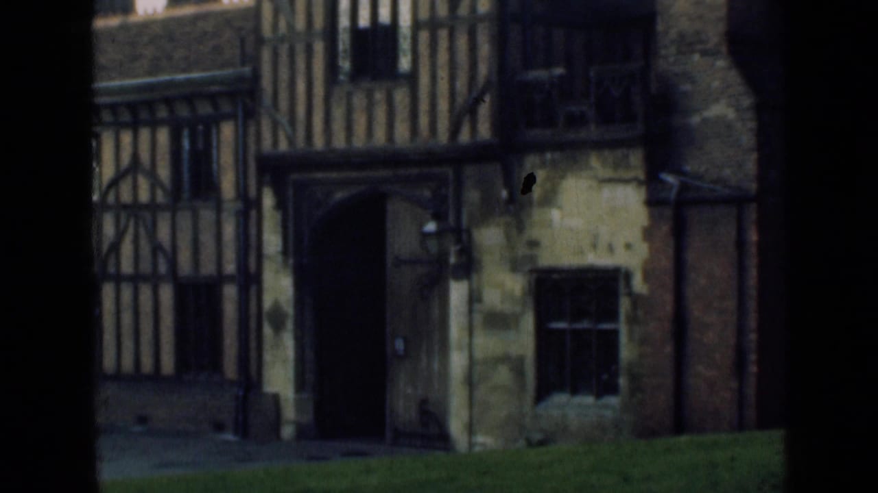 1946 8mm exterior view of a Tudor-style timber-framed facade with a dark arched entrance and stone wall sections.