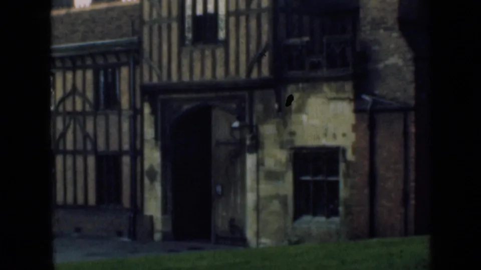 1946 8mm exterior view of a Tudor-style timber-framed facade with a dark arched entrance and stone wall sections.