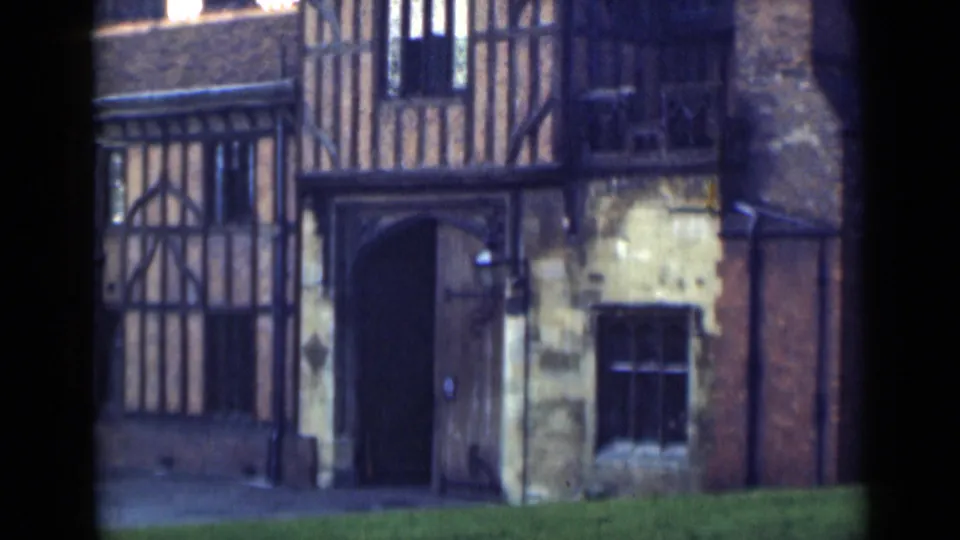 Closer 1946 home-movie frame of the historic timber-framed exterior, centered on the arched doorway and adjacent window.