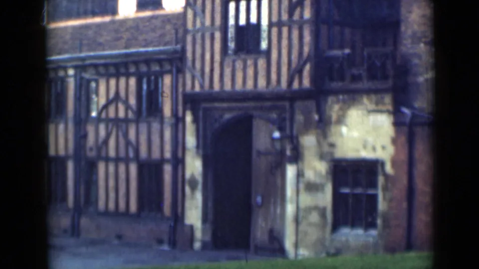Final 1946 8mm frame holds on the timber-framed building exterior with arched entrance, window and narrow green foreground.