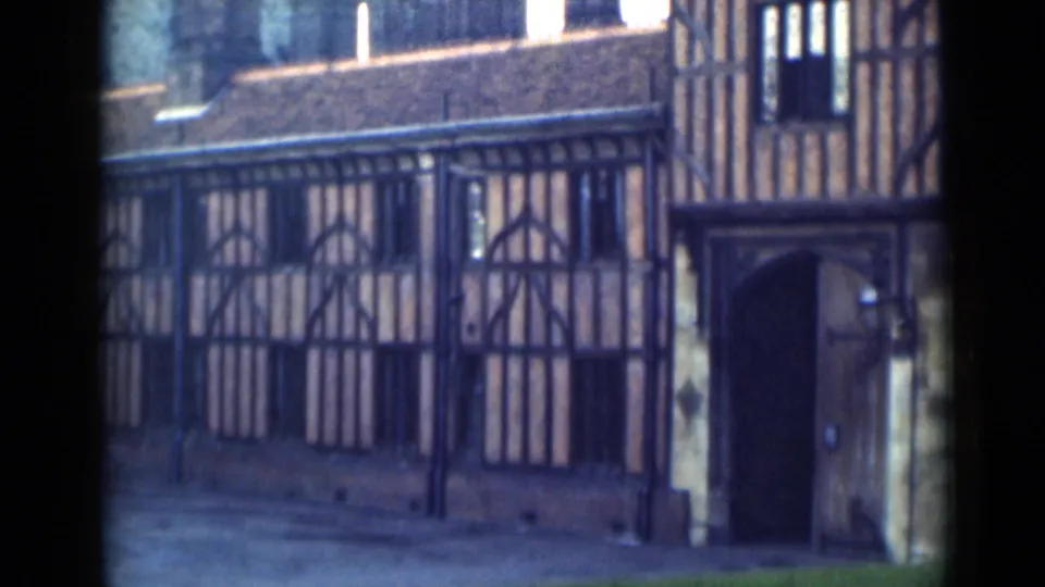 Final 1946 London frame showing the same timber-framed building, with railings across the front and the arched doorway at right.