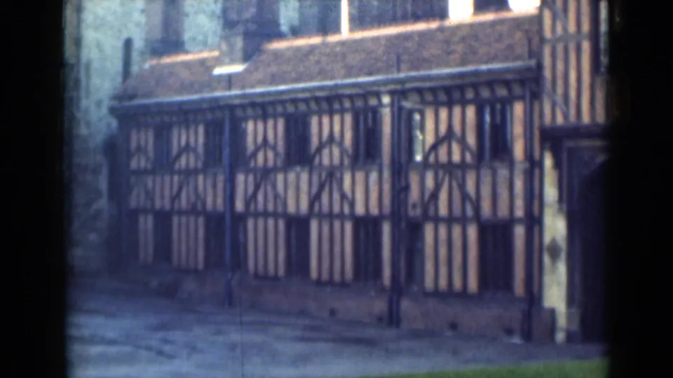 1946 London frame holding on the half-timbered exterior, pale wall panels, roof tiles, and an empty paved foreground.