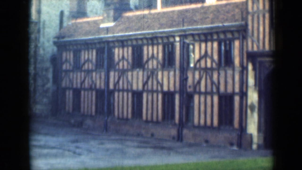 1940s 8mm visitor view showing a timber-framed facade near Windsor Castle, partly obscured by a dark window or doorway edge.