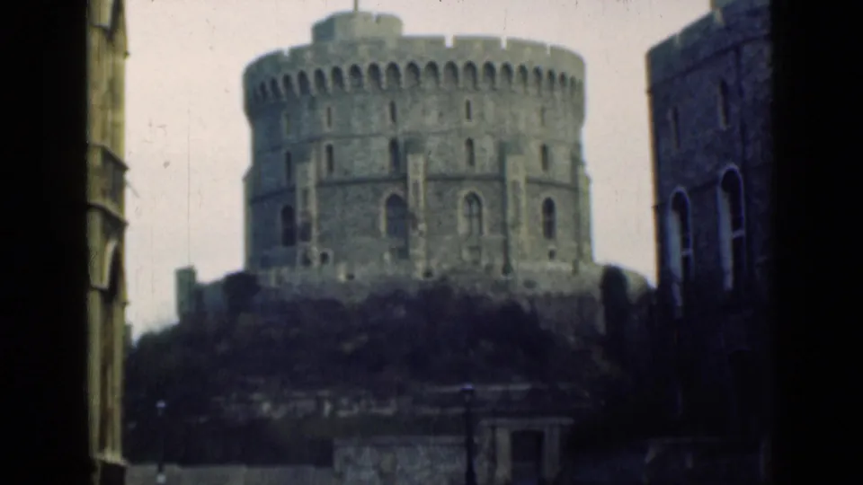 1940s 8mm view of Windsor Castle's Round Tower, with hillside planting and nearby stone structures in the foreground.