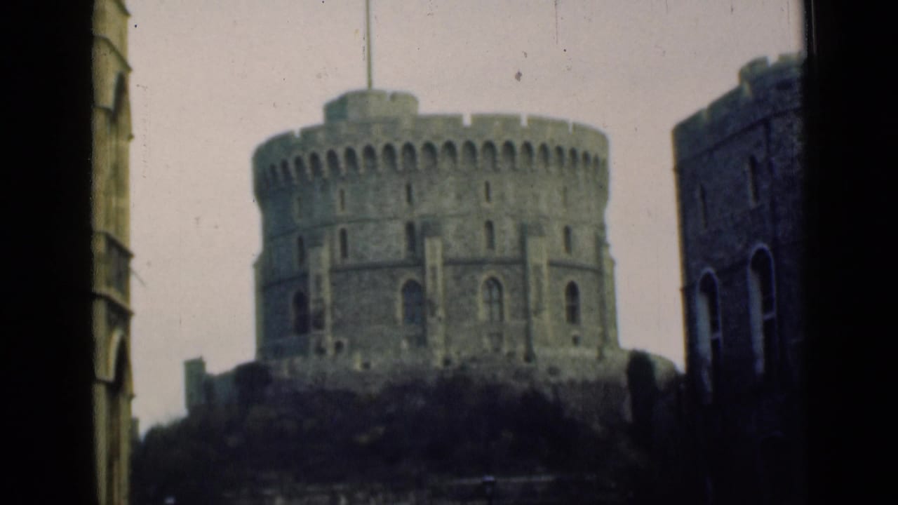 Round stone castle tower with a flagpole, framed by dark vertical edges and adjacent stonework.