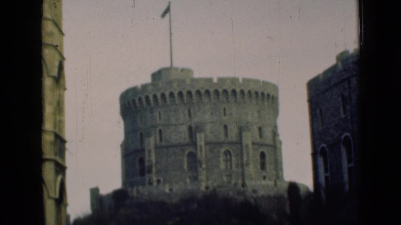 Soft 8mm frame of the Windsor Castle Round Tower with flag above, bordered by dark foreground edges and nearby castle masonry.