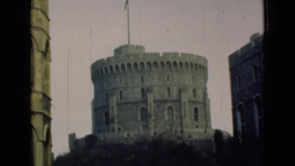 Final 8mm frame holds on Windsor Castle's Round Tower and flag, with nearby masonry at right and visible grain and scratches.