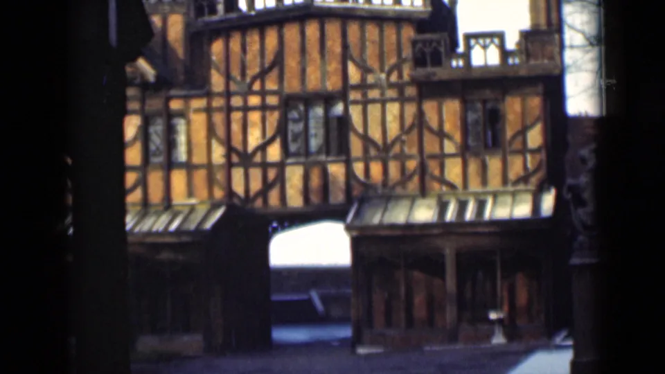 The clip ends on a timber-framed Tudor-style building, with arched lower opening and dark foreground edges.