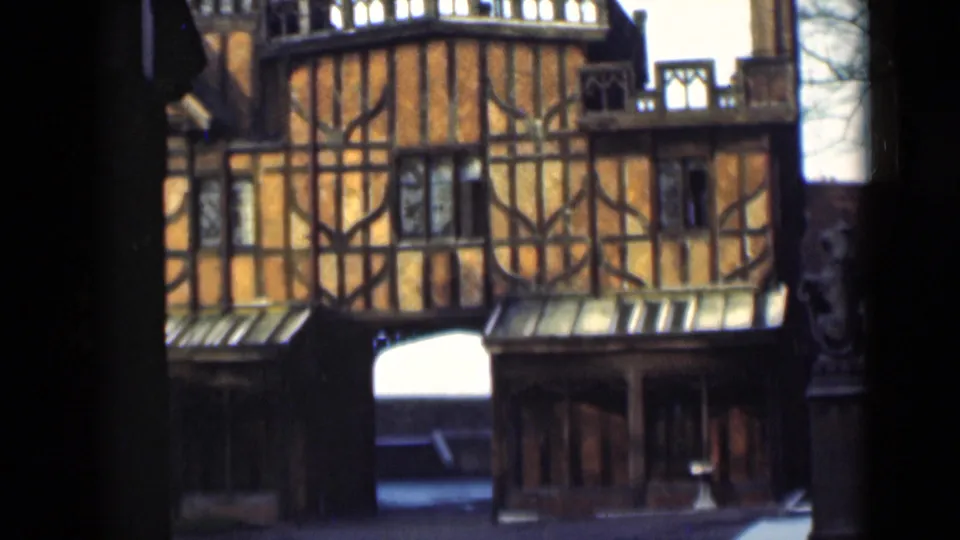 1946 London home-movie frame with a slight camera shift across the orange timber-framed building and central arch.