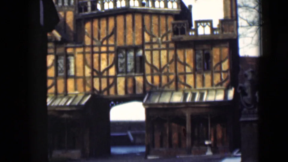 1946 London frame holding on the orange timber-framed facade, central passage, lower bays, and dark foreground framing.