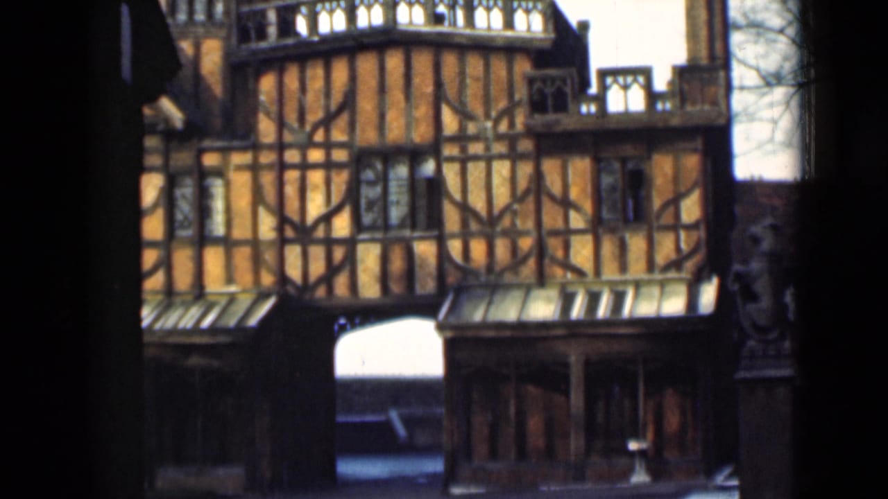 1946 London home-movie frame showing a Tudor-style timber-framed facade with leaded windows and arched passages.