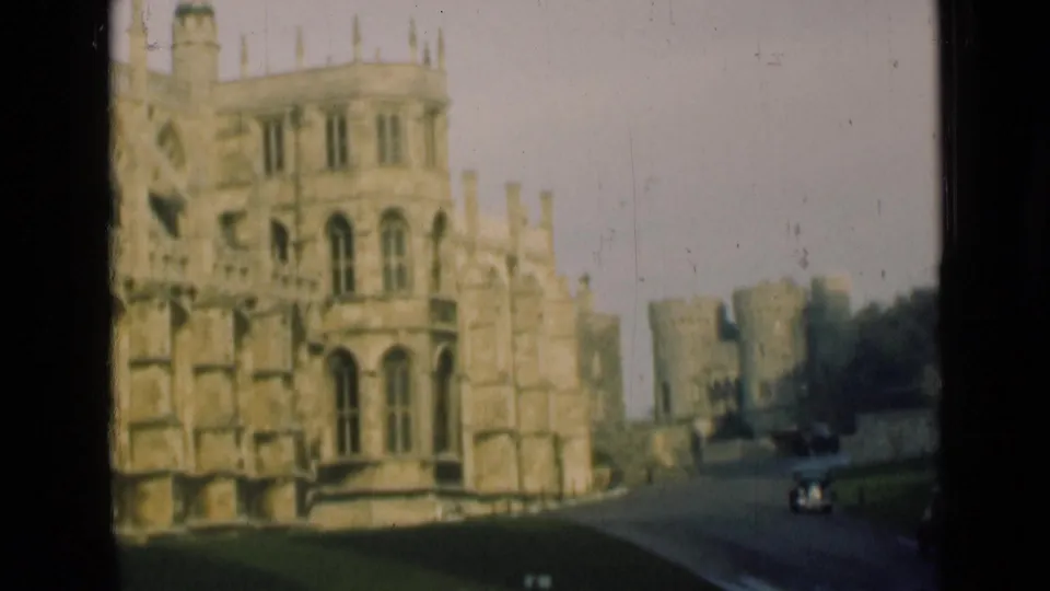 1946 England home-movie frame showing a royal castle exterior with stone towers, battlements, road, lawn, and classic cars.
