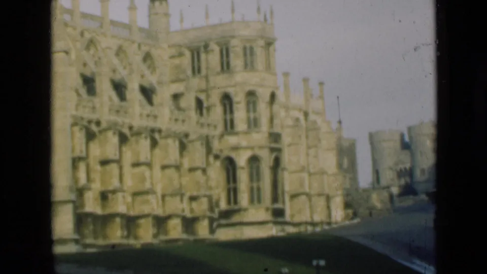 1946 London-area 8mm view of a Gothic castle exterior, distant turreted walls, roadway, and visible film surface marks.