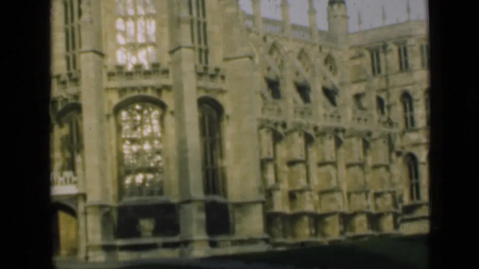 1946 London-area frame showing a large Gothic window, pale stone wall, buttresses, and formal lawn in faded 8mm color.