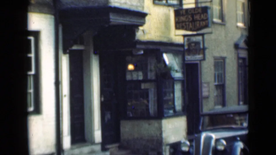 End frame of a 1946 London home movie showing Ye Olde King's Head frontage, hanging sign, lit window, and parked car.