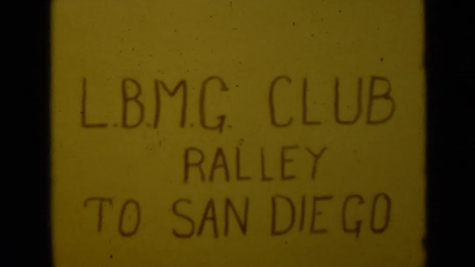 A second view of the handwritten L.B.M.G. Club rally to San Diego title card on warm, aged 8mm film.