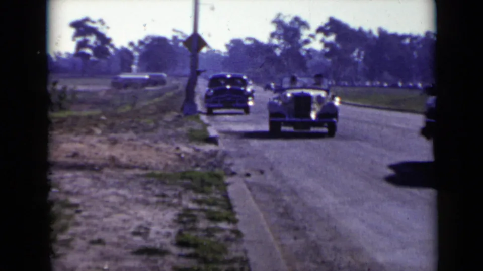 A light-colored convertible and a dark sedan appear on a suburban San Diego road in this 1949 home-movie frame.