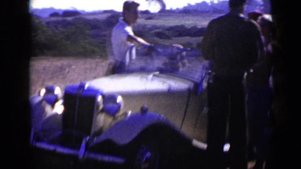 1949 San Diego frame with a softly focused antique convertible roadster and adults standing near the passenger side.