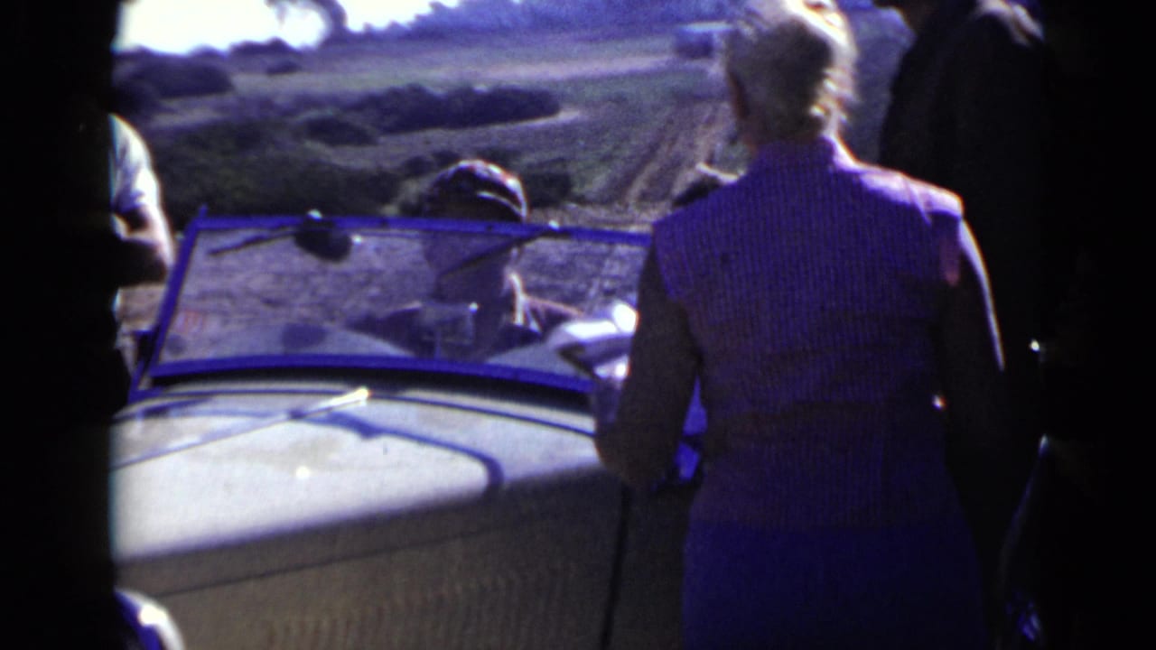 Light convertible viewed close up with a woman standing beside it.