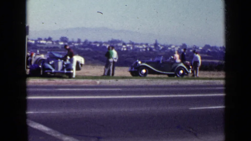 San Diego, 1949, with adults examining parked vintage cars near a roadside and open landscape.