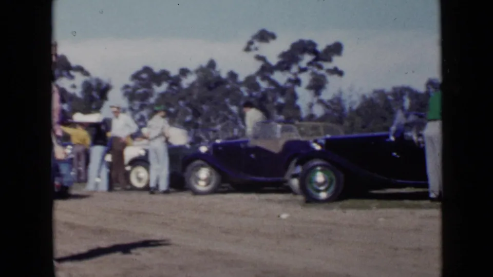 Wide 1949 San Diego view of several people gathered near vintage open-top cars on a dirt track or lot.