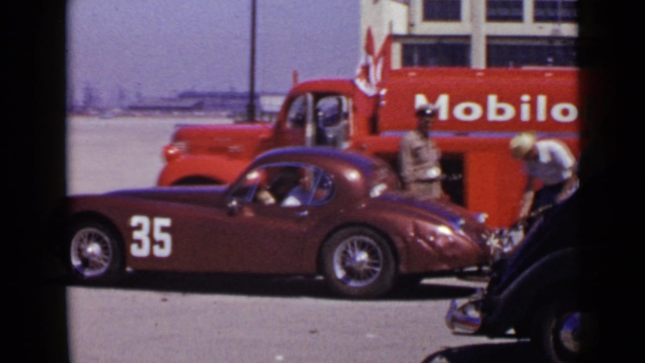 1949 San Diego frame with the number 35 maroon racing car in profile, a red Mobil oil truck behind it, and people nearby.