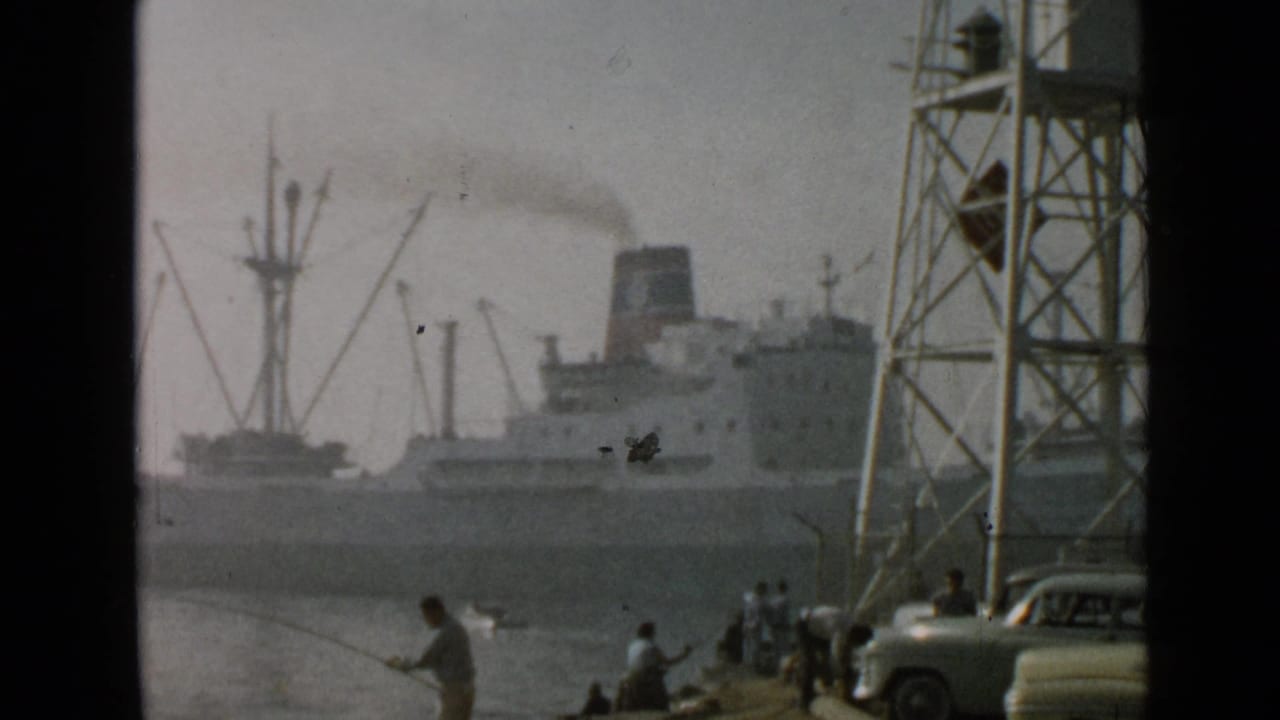 Harbor ship with smoke behind fishermen, cranes, tower structure, and waterfront spectators.