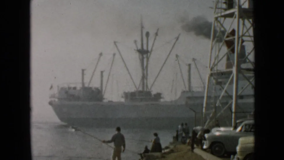 1949 San Diego waterfront footage showing a smoking cargo ship behind fishermen, small groups of people, cranes, and classic cars.