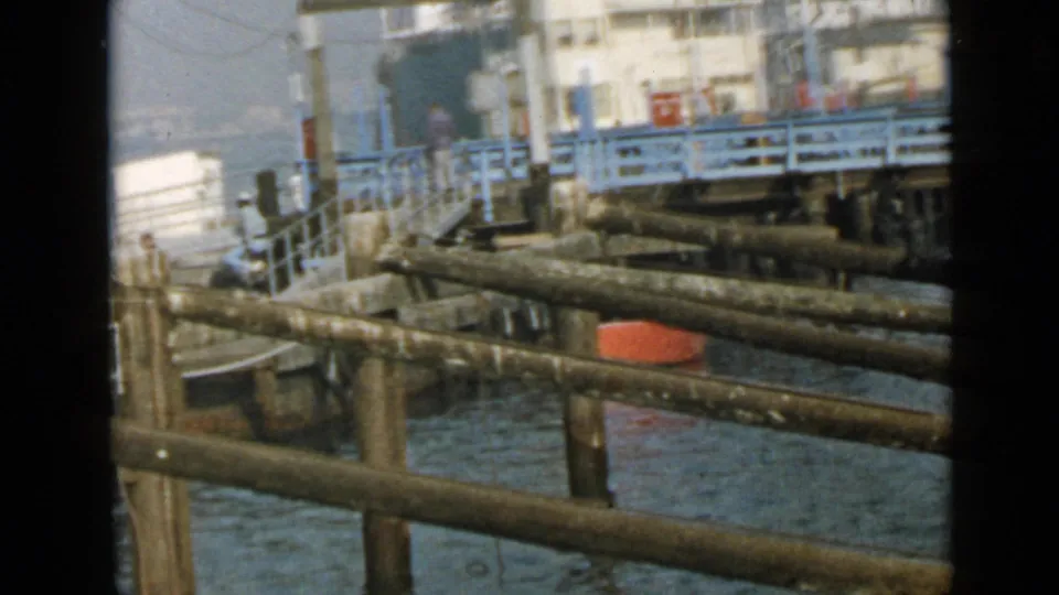 1949 San Diego waterfront frame showing wooden railings, water, dock structures, and buildings, likely from the same home-movie sequence.
