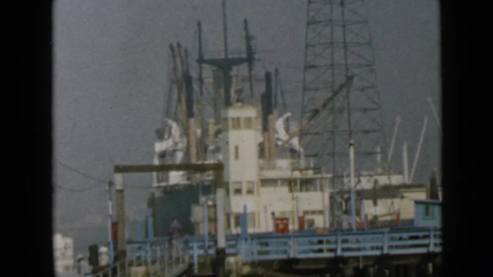 Soft 8mm view of a docked ship at the San Diego port, with mastwork and blue railing across the foreground.