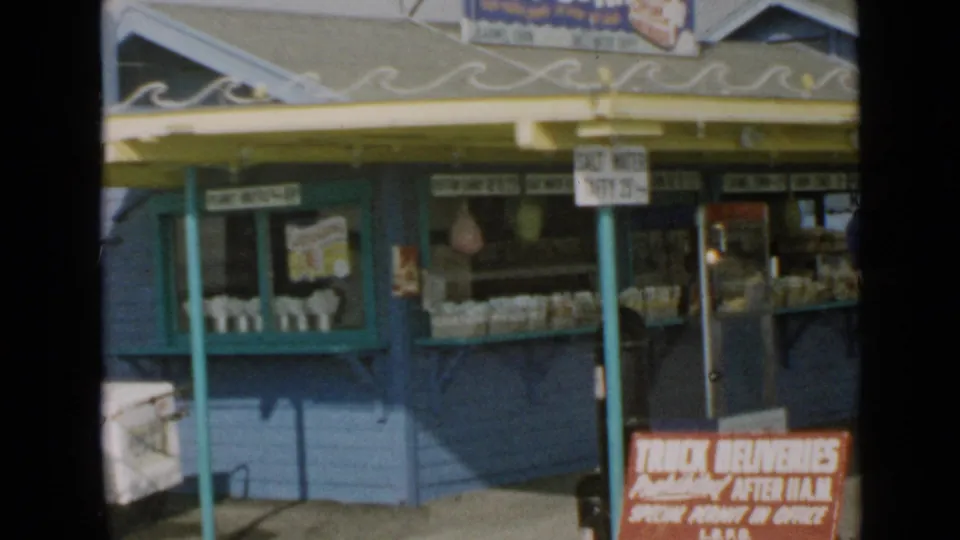 1949 San Diego seaside concession stand with blue walls, yellow trim, snack displays, and visible posted signage.