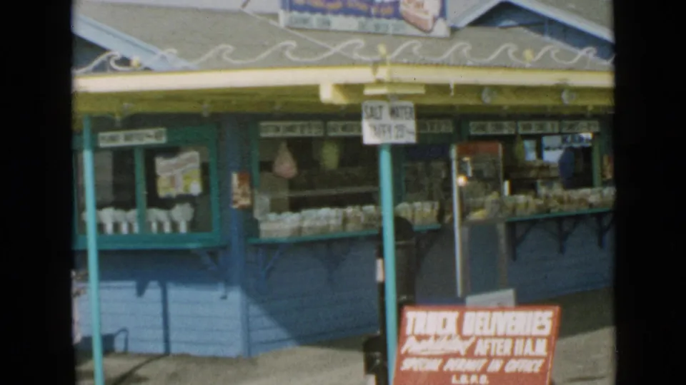San Diego seaside stand showing salt water taffy signage, counter displays, and a partially visible person at the edge of frame.