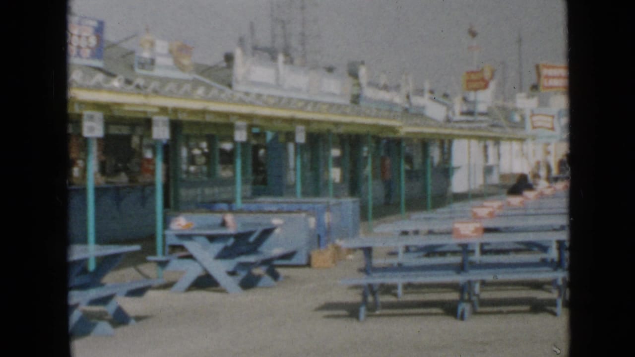 San Diego pier concessions and blue benches appear in soft 8mm color, with signage above the counters.