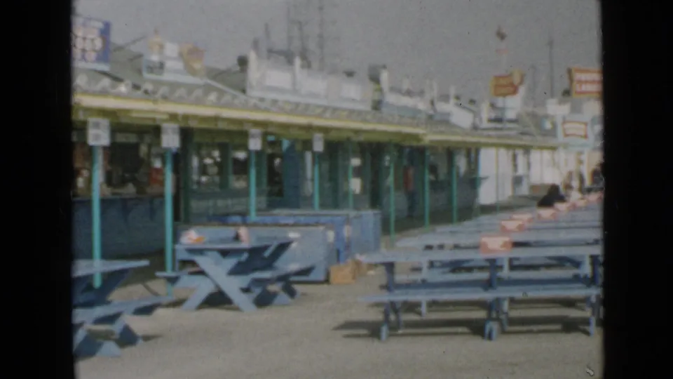 San Diego pier concessions and blue benches appear in soft 8mm color, with signage above the counters.