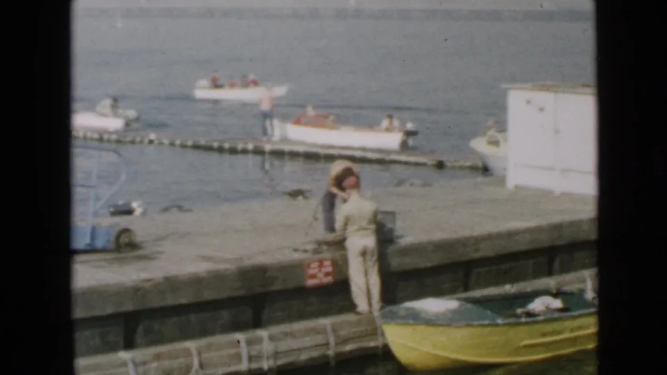 1949 San Diego home-movie view of a pier with a person in light clothing and small boats offshore.